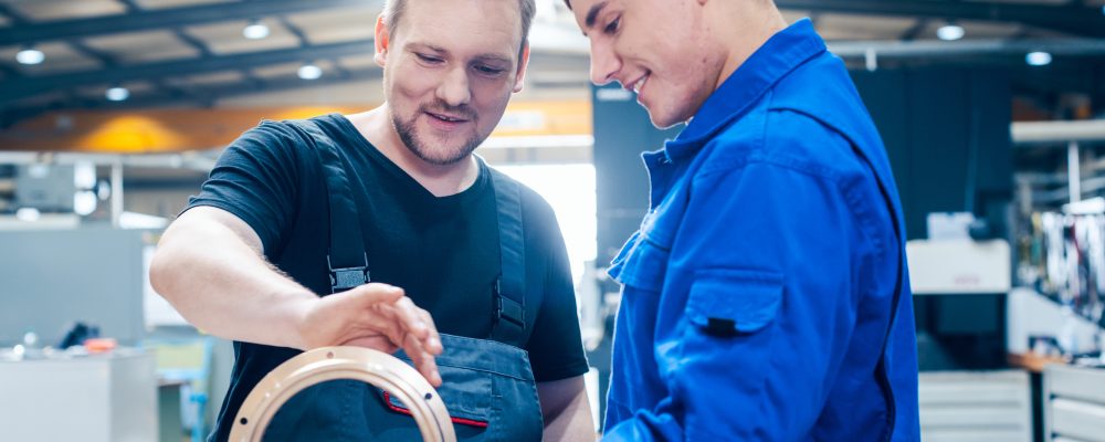 Master discussing a workpiece with his apprentice or trainee Montage Ihrer Klimaanlage Celle